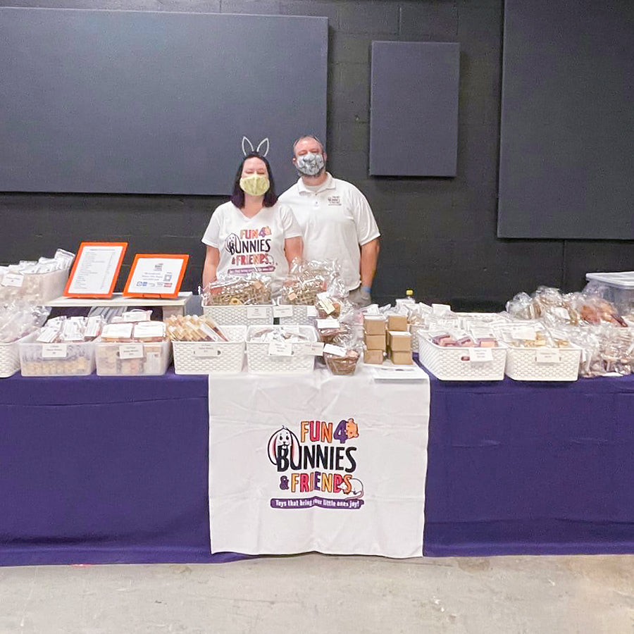 Fun4Bunnies & Friends owners standing behind an event table at Midwest BunFest. 